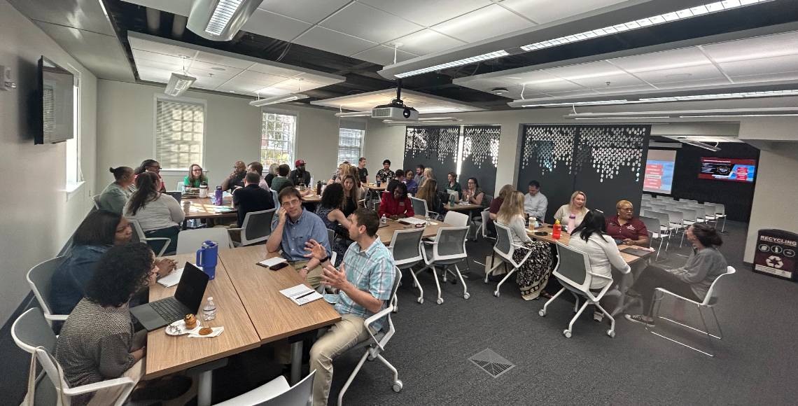 Staff and faculty sitting at tables talking with one another.