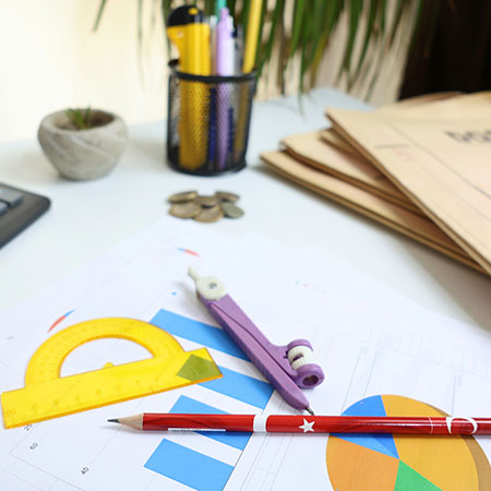 math supplies like a protractor, pencil, and compass are laying on a table