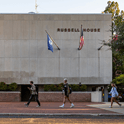 individuals walking in front of Russell house building on university campus 