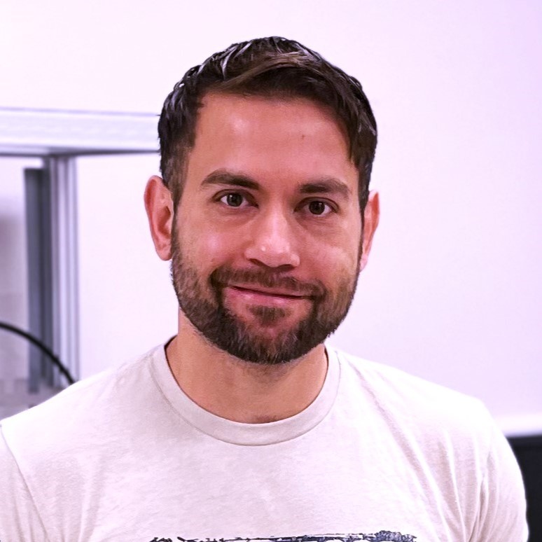 young white man with dark hair, wearing white tshirt in front of white wall