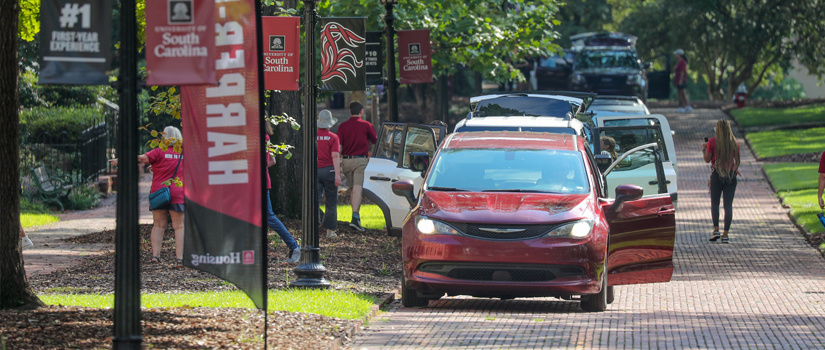 Vehicles pulled along the historic horseshoe unloading during move in as volunteers assist with unloading cars.