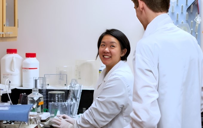 Two researchers smile as they work together in a laboratory setting.