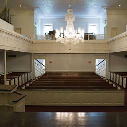 A chapel with wooden pews and a chandelier.