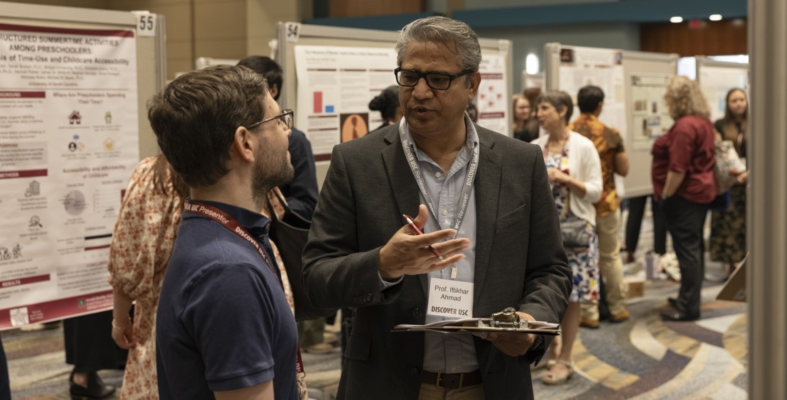 A graduate student presenter discusses his poster with a reviewer at Discover USC 2025.