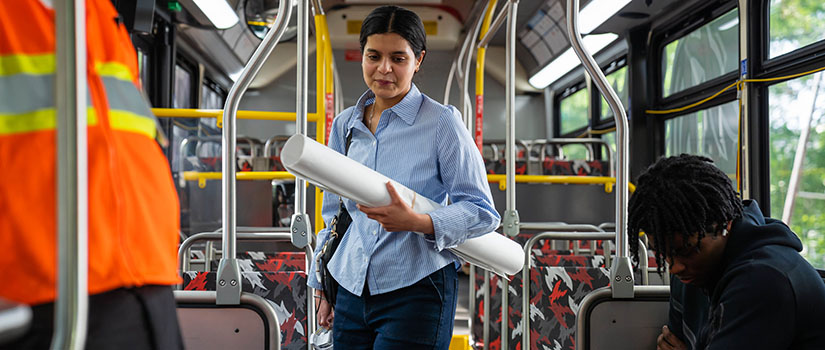 A Discover USC presenter, dressed in professional attire, carries her poster onto a shuttle bus on her way to present at the Columbia Metropolitan Convention center.