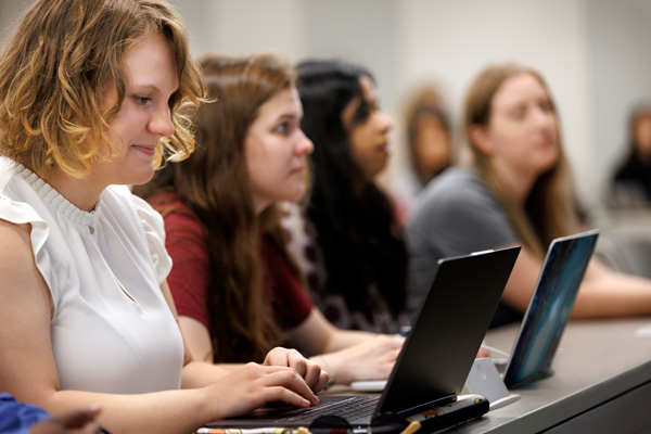 students listening to a lecture with laptops on table