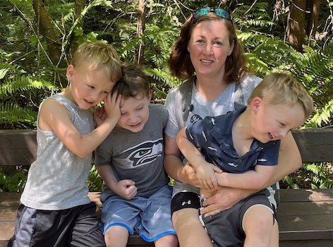 Kate Bowman smiles at the camera while surrounded by her three young sons.