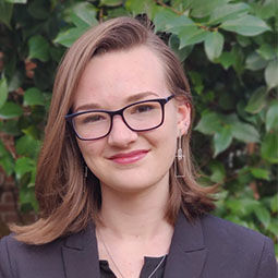 a woma with light brouwn hair stands outside smiling