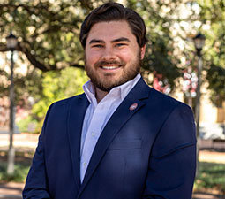 a photo of a man smiling wearing a navy blue blazer