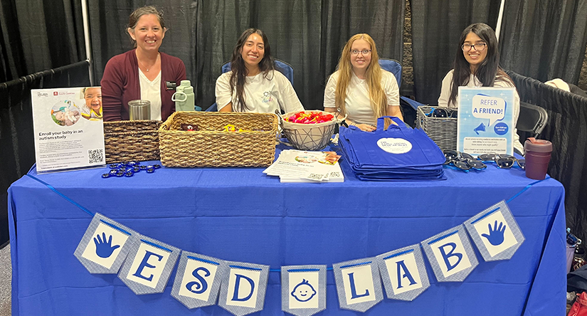 Group of University of South Carolina students and staff at an AutismConnect booth with informational materials, tote bags and giveaways at a conference table