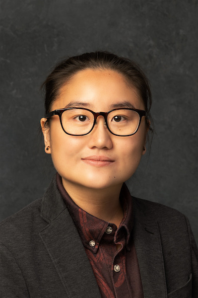 woman standing outside with glasses and blue blazer on with a colorful shirt