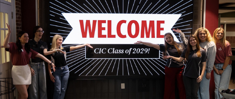 Students in front of a sign that says Welcome