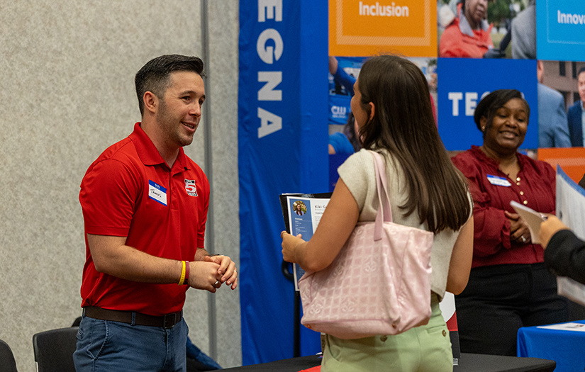 student and professional chatting at career fair