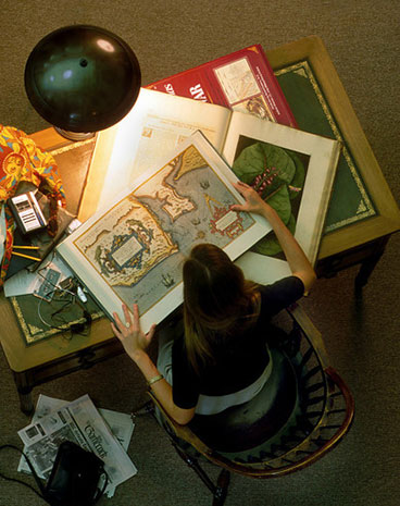 a woman consults a map by the light of a single lamp