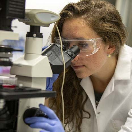 a female syudent looks into a microscope