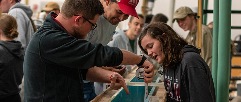 students stand over water testing sluice