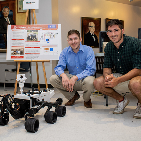 two students display the rover in the lobby