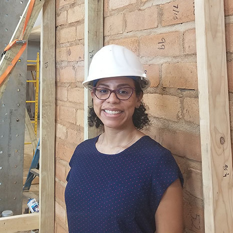 Headshot of woman in front of a wall wearing a hard hat