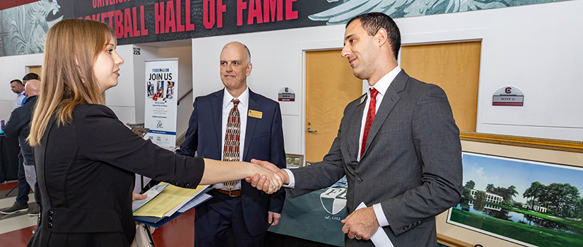 A student shakes the hand of a company recruiter at the Experience Expo job fair.