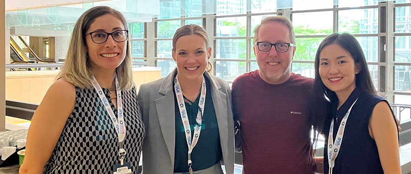 Four people attending a research conference pose for a photo.