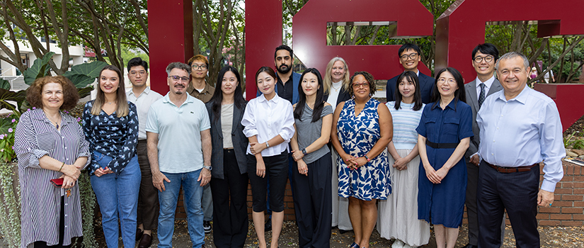Members of the Ph.D. in hospitality management program pose for a photo in front of USC letters.