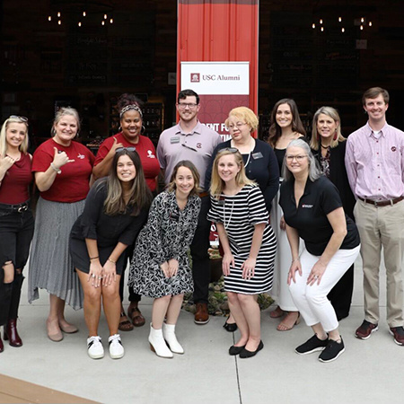 A group of HRSM staff and alumni pose for a photo outside of a restaurant.