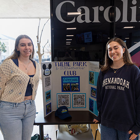 Two students pose in front of a table at a student organization fair