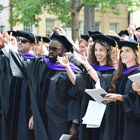 Students smiling at commencement and wearing their graduation regalia.