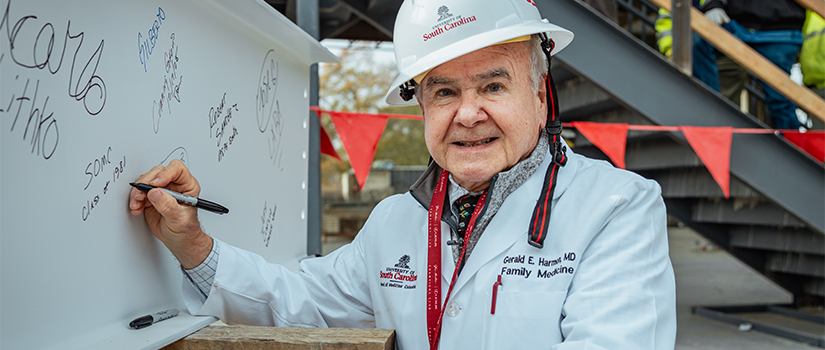 Dean Gerald Harmon signing the final beam of the new school of medicine facility
