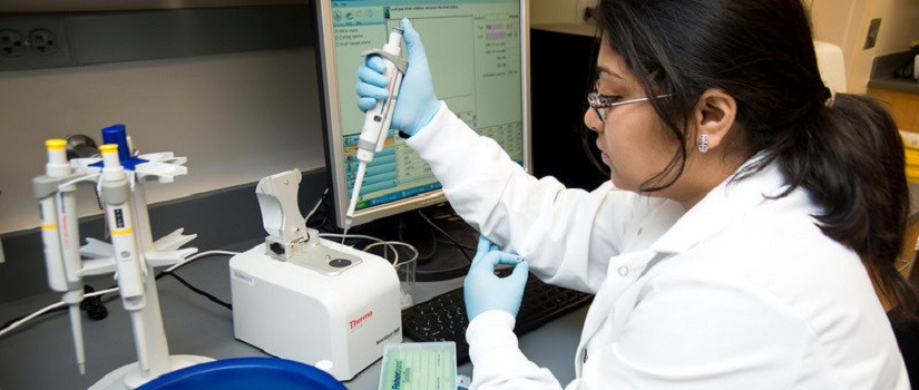 Woman in lab coat working with medical equipment