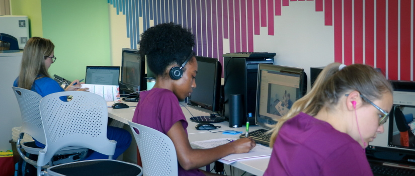 Students sitting at computers conducting remote speech and hearing evaluations