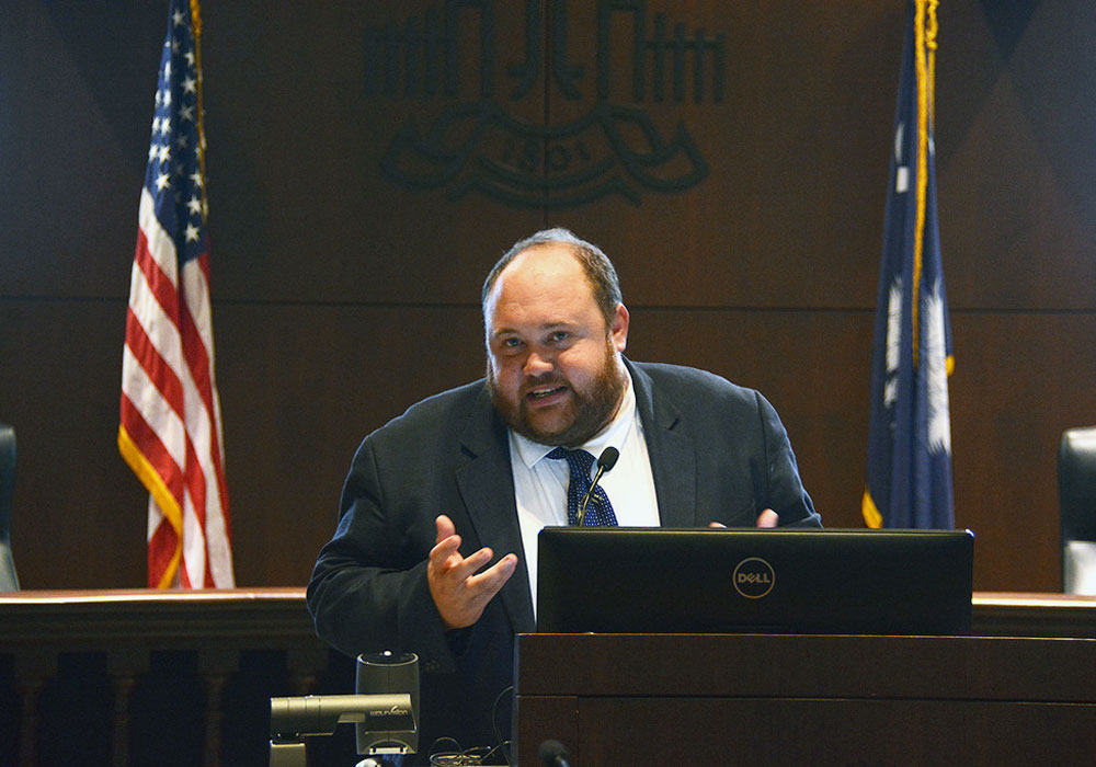 man gestures while speaking at a podium