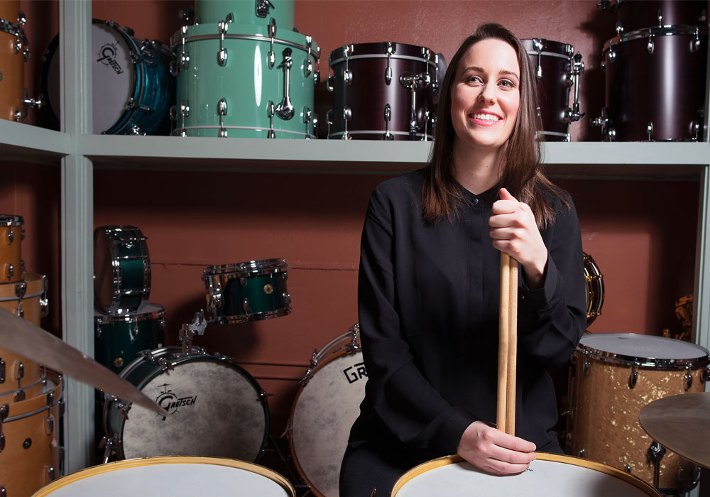 woman stands in a room filled with drums