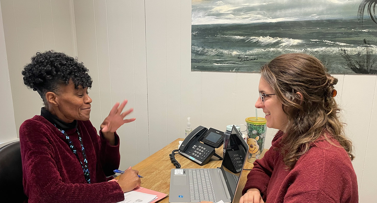 Renee Shaw sits at her desk across from a patient.