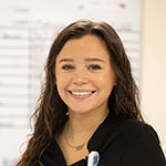 Makenzie Edwards smiles at work in front of a white board