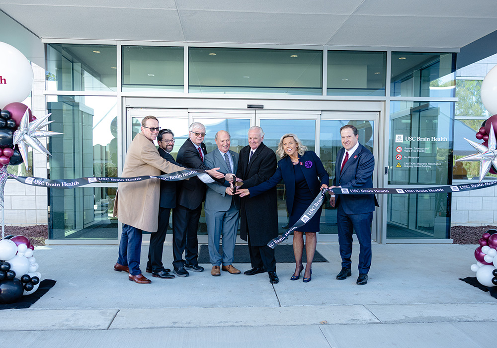 official cutting a ribbon in front of a center