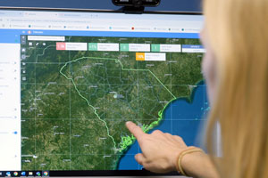 a woman points at a computer screen with a map of south carolina on it