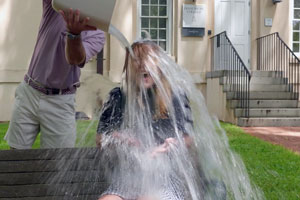 two people outside with one pouring water over the other's head