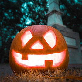 Warmly lit jack o'lantern sitting in grass on the Historic Horseshoe