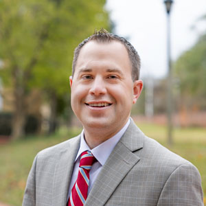 A headshot of Ryan Rucker in a suit outside Davis College