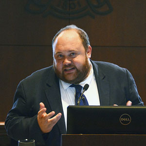 man gestures while speaking at a podium