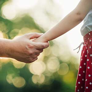 Parent reaches out hand to hold daughter's hand. 