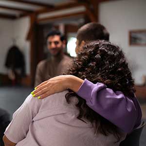 Woman offers comforting embrace to peer during group counseling session