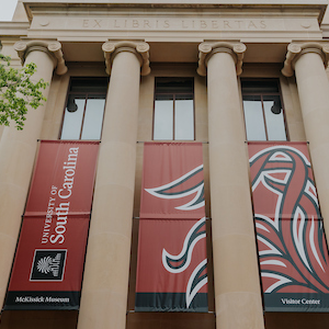 Beige building with columns with sign that reads university of south carolina, mckissick museum, visitor center