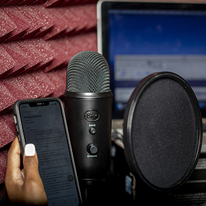 A person holds a phone next to audio recording equipment in a studio.