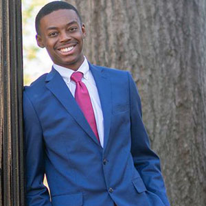 Jordan Richardson leans against a lightpole with a tree in the background
