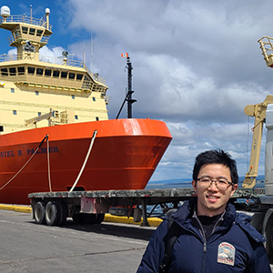 Asian man standing on dock in foreground with ship visible behind him