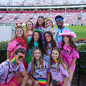 Students in bright colored clothes for Dance Marathon pose at the USC football stadium