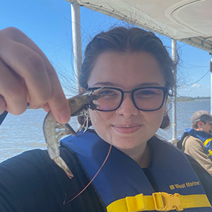 Alexis Yum holding a shrimp at Baruch Institute