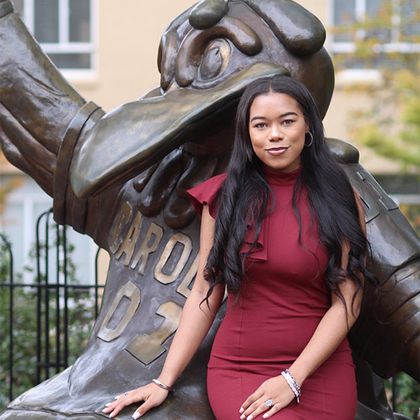 Woman in red dress sits near Cocky statue
